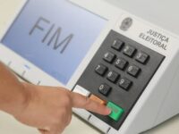 Urna eletrônica utilizada nas eleições brasileiras, com orientações sobre horários, documentos e regras para votar no segundo turno.